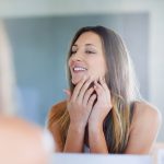 woman-mirror-pimple-skincare-bathroom-cosmetic-beauty-routine-grooming-hands-smile-chin-facial-acne-reflection-clean-dermatology-female-person-home